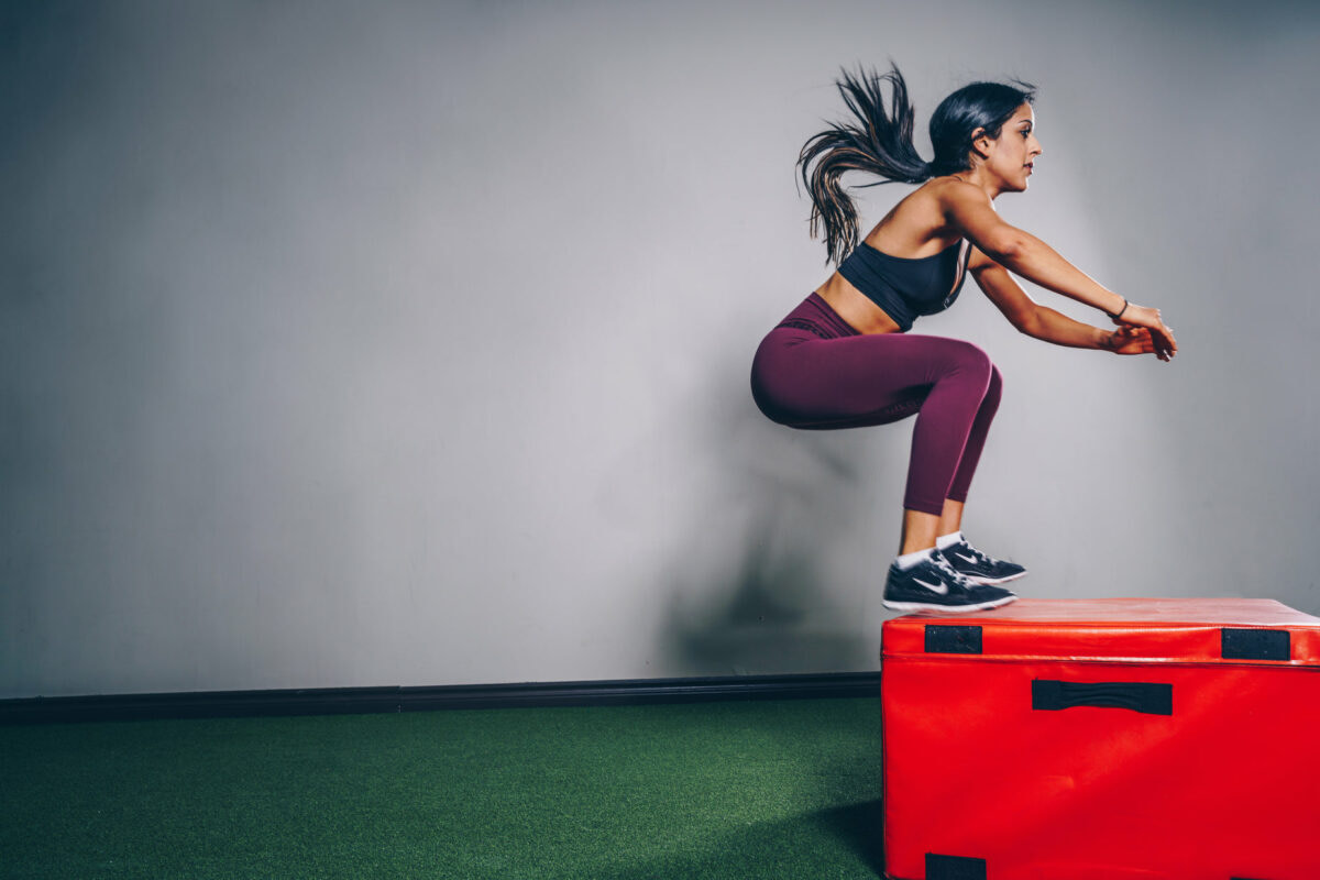 a woman jumping over a box