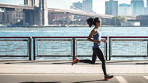 a woman running on a sidewalk near water