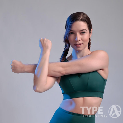 a woman in green workout outfit stretching her arms