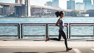a woman running on a sidewalk near water