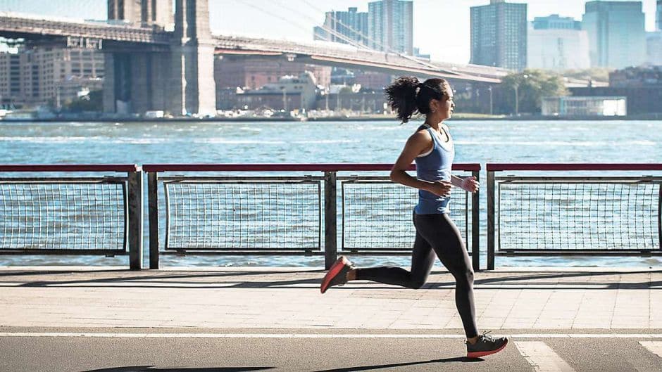 a woman running on a sidewalk near water