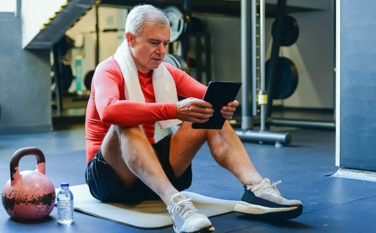 a man sitting on a mat looking at a tablet