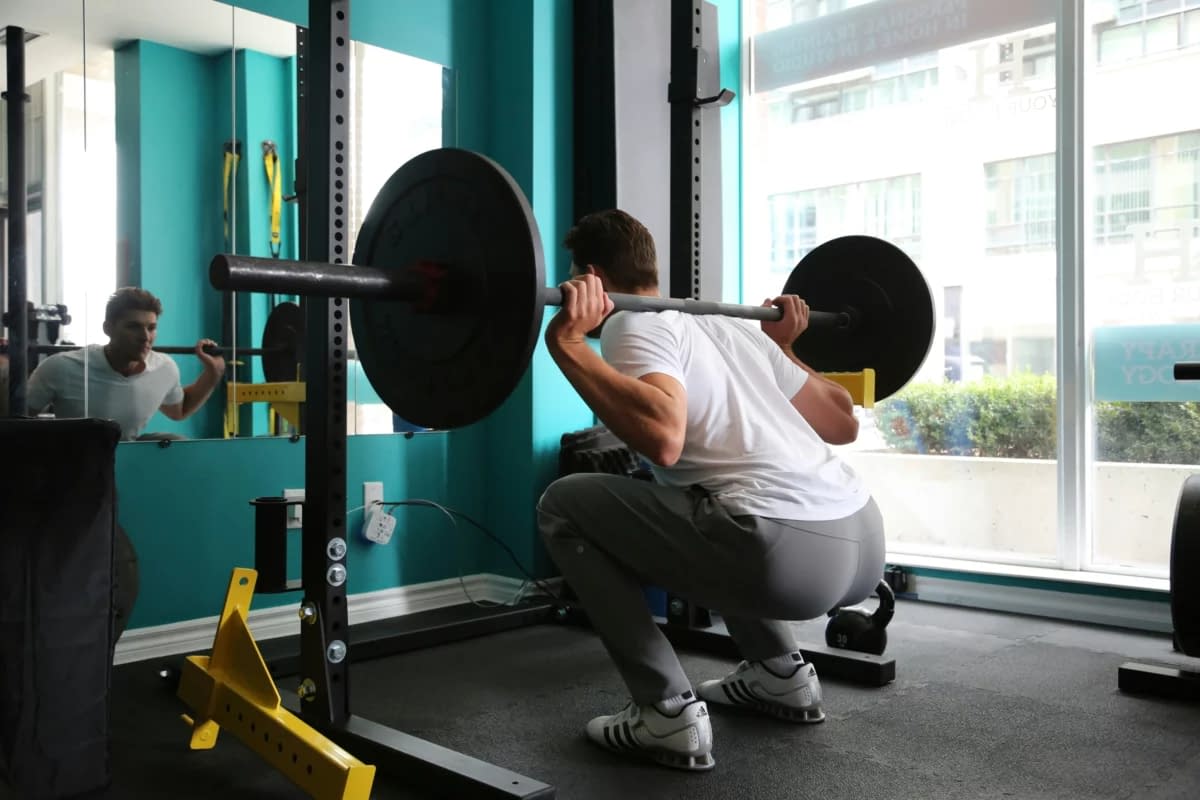a man squatting with a barbell over his head