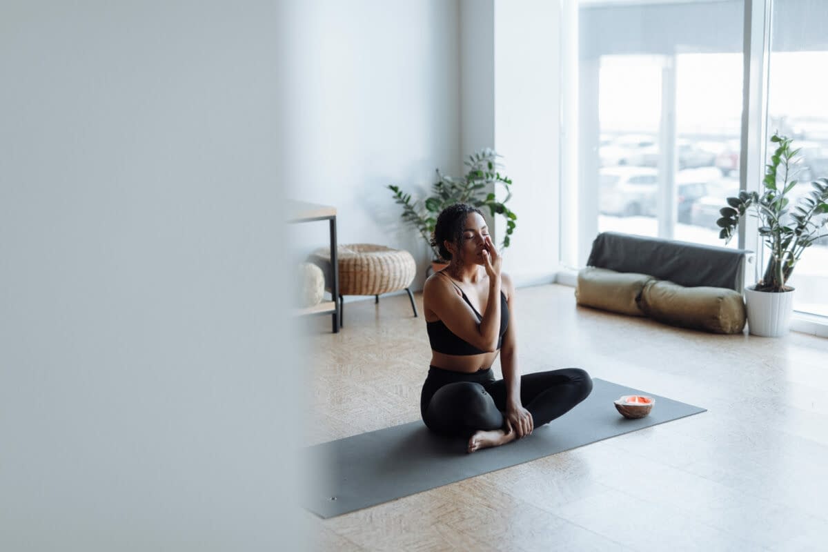 a woman sitting on a yoga mat and doing yoga breathing