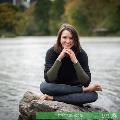 a woman sitting on a rock by water