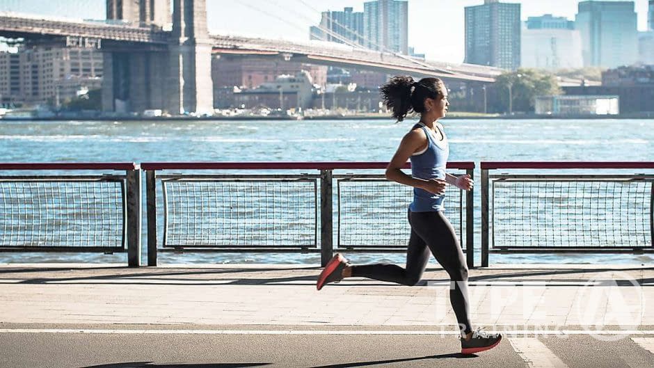 a woman running on a sidewalk near water