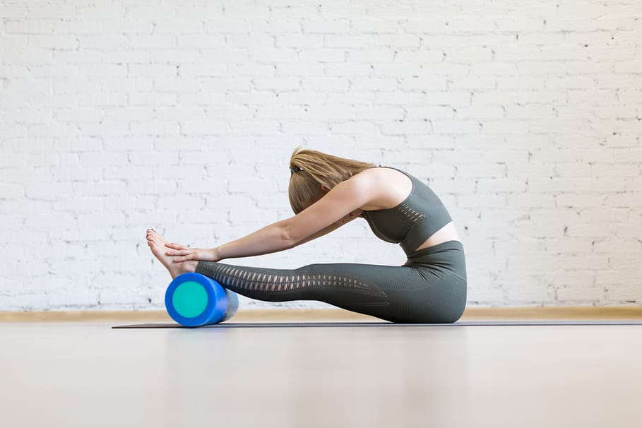 female runner stretching on a foam roller to prevent running injuries