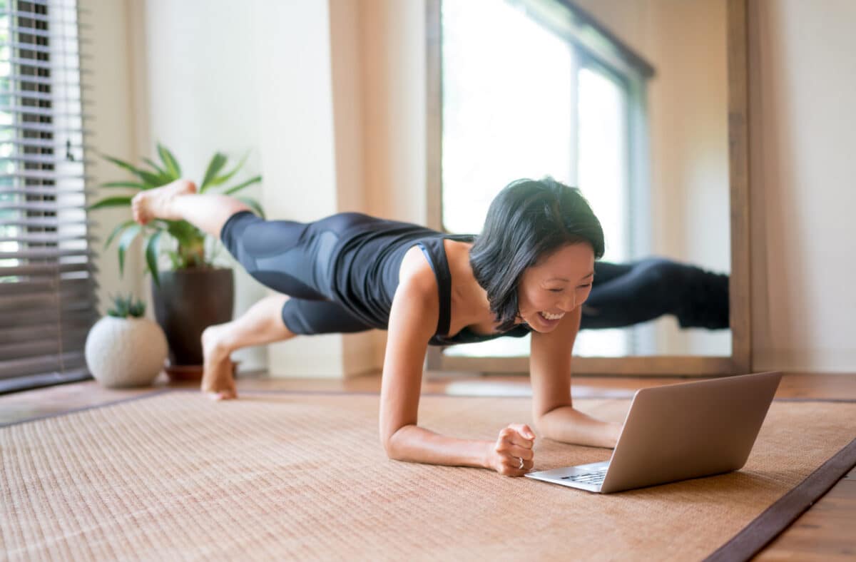 a woman doing plank on the floor with a laptop